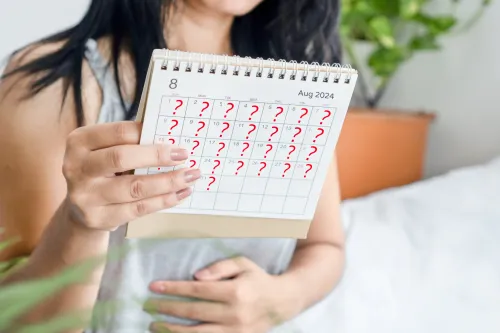 Woman holding a calendar marked with question marks, indicating uncertainty about a missed period.